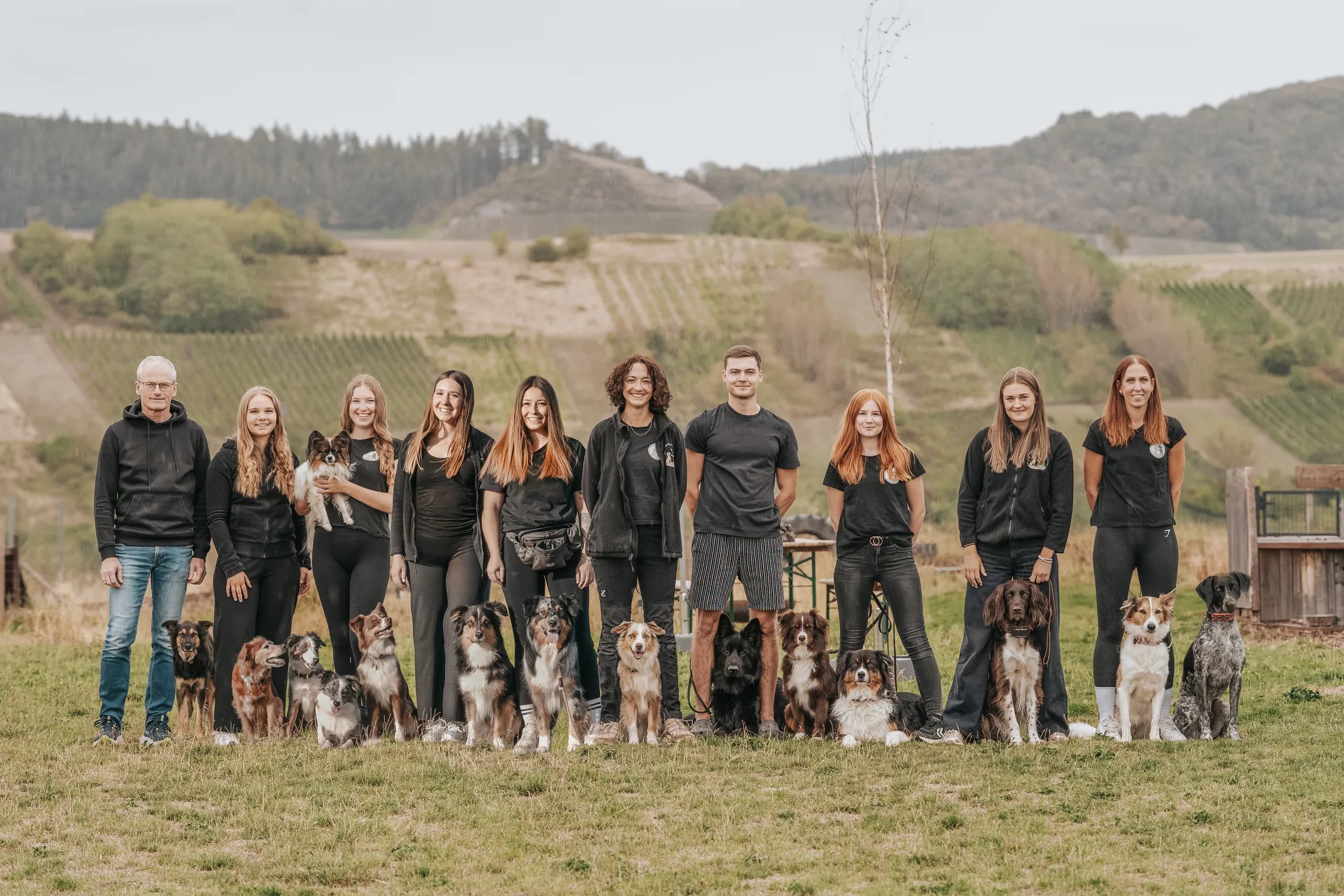 Das Team des Hundezentrums mit seinen Hunden vor den Weinbergen