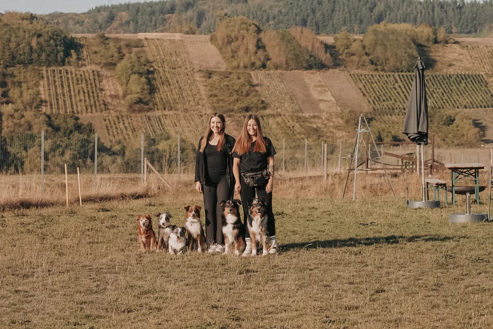Michelle und Lisah stehen mit fünf Hunden vor den Weinbergen